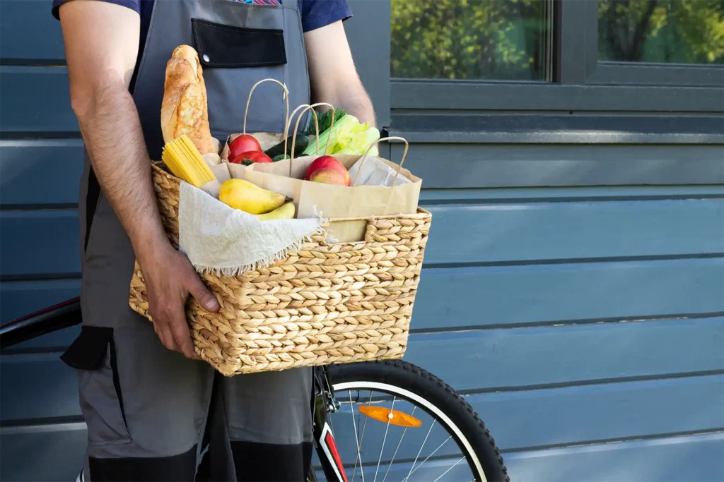 Livraison de courses avec produits frais dans un panier en osier, service personnalisé de la conciergerie de La Plume du Cap au Cap-Ferret