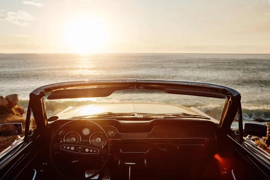 Voiture décapotable face à l’océan au coucher du soleil, service de location automobile de la conciergerie de La Plume du Cap