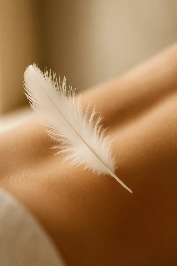 Plume blanche déposée sur un dos nu, illustration de la douceur et du bien-être au spa de La Plume du Cap